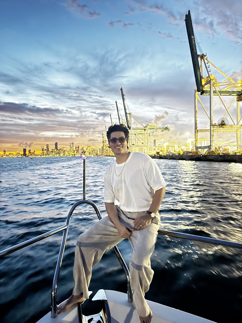 De La Plata smiling on a boat with the waterfront behind him at sunset